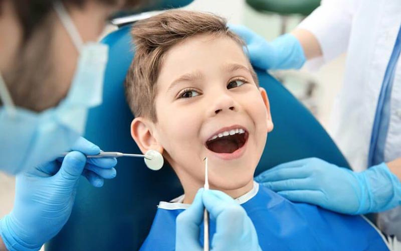 Niño sonriente en la silla dental durante una revisión odontológica