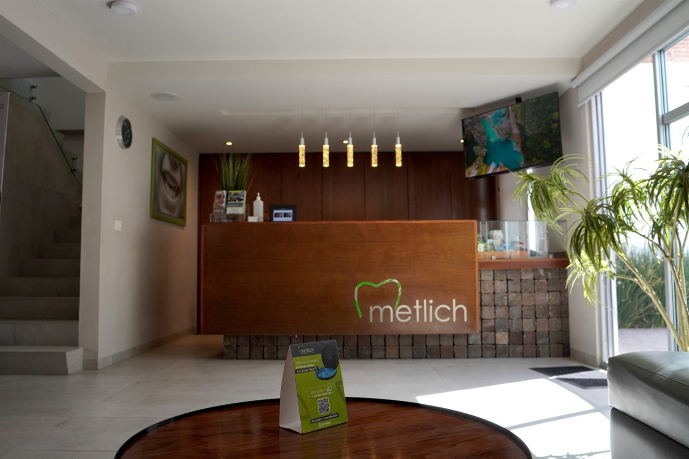 Recepción y sala de espera de METLICH Centro de Odontología, con mostrador de madera y el logotipo de la clínica